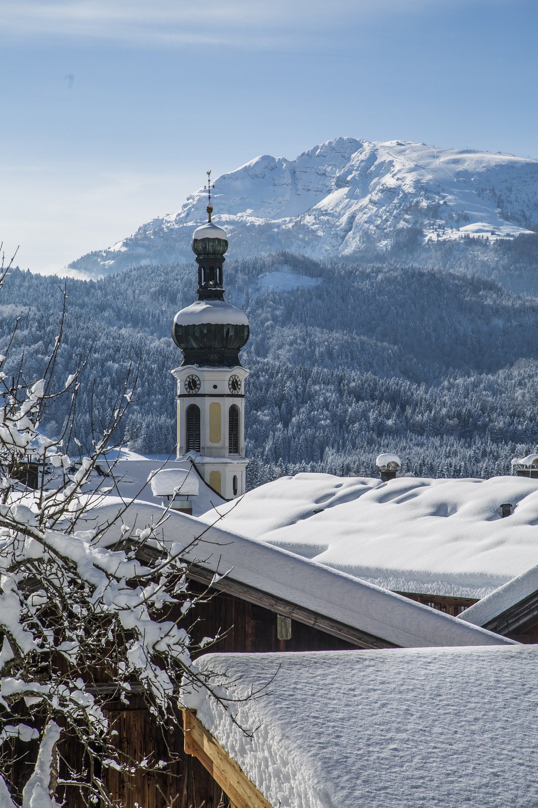 View of a snow-covered church in Reit im Winkl in the sunshine