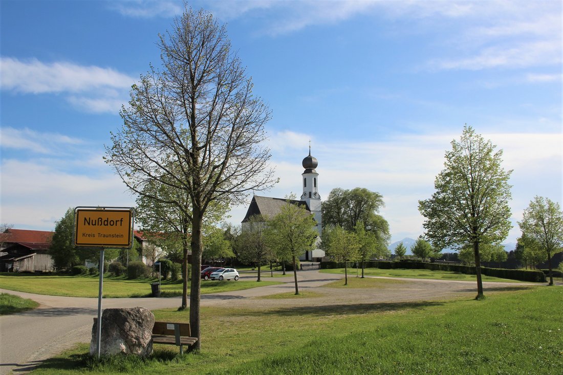 Ortseingang Nußdorf mit Ortsschild und Blick auf den Kirchturm