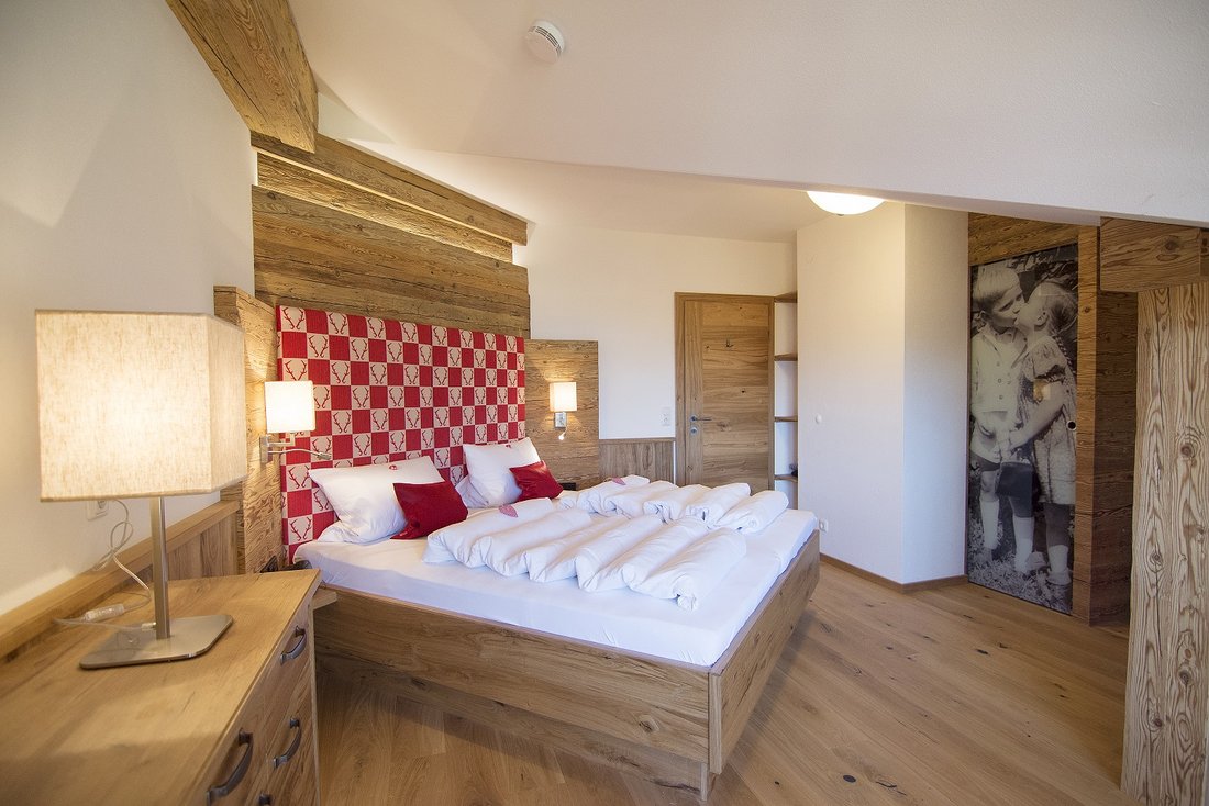 Alpenländischer Luxus im Stadl-Stil mit Massivholzbett und begehbarem Kleiderschrank. Hier lässt es sich herrlich träumen!