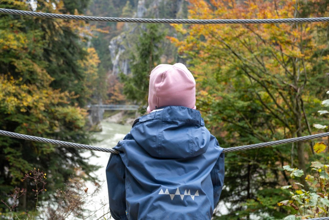 Kind schaut von einer Hängebrücke auf die Tiroler Ache