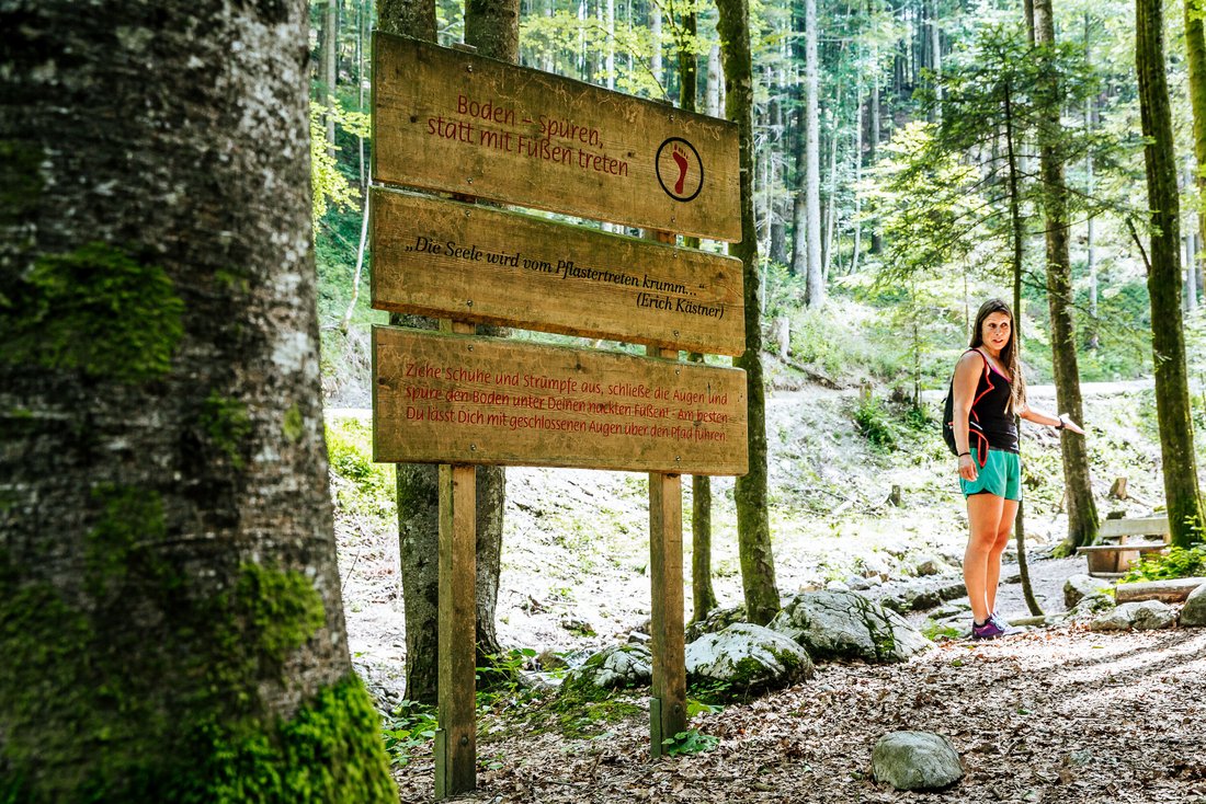 Frau vor Wegweiser im Bergwald-Erlebnispfad in Inzell