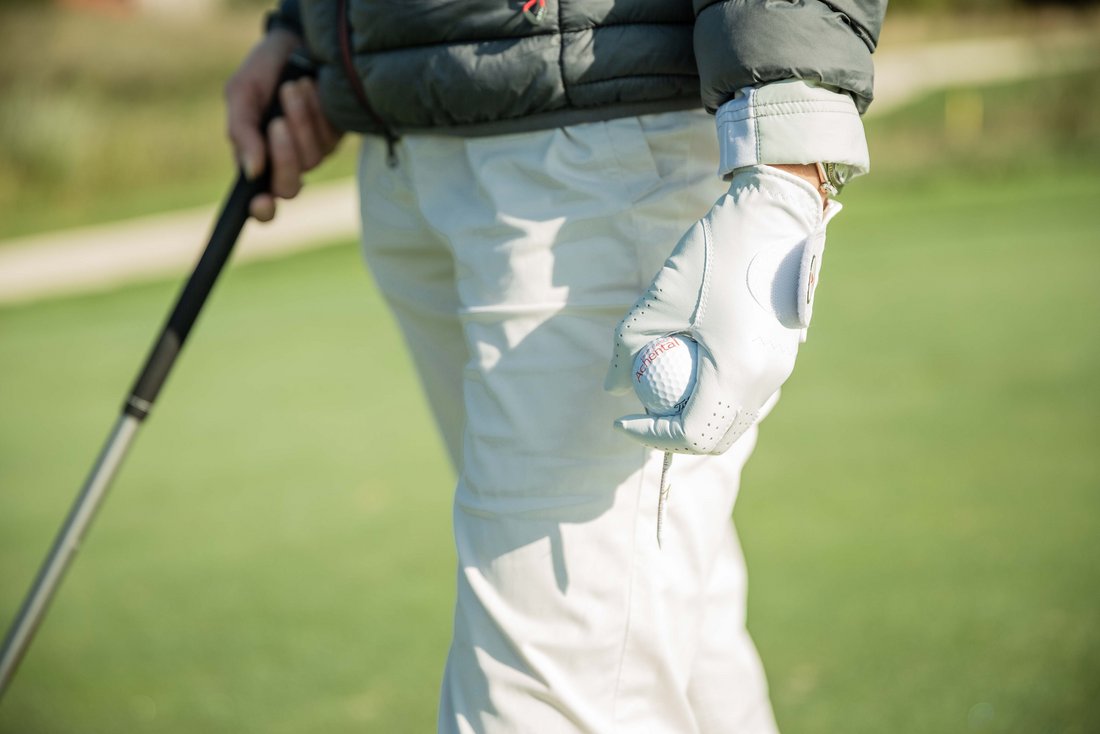 Golferin hält Golfball und Schläger im Golfresort Achental