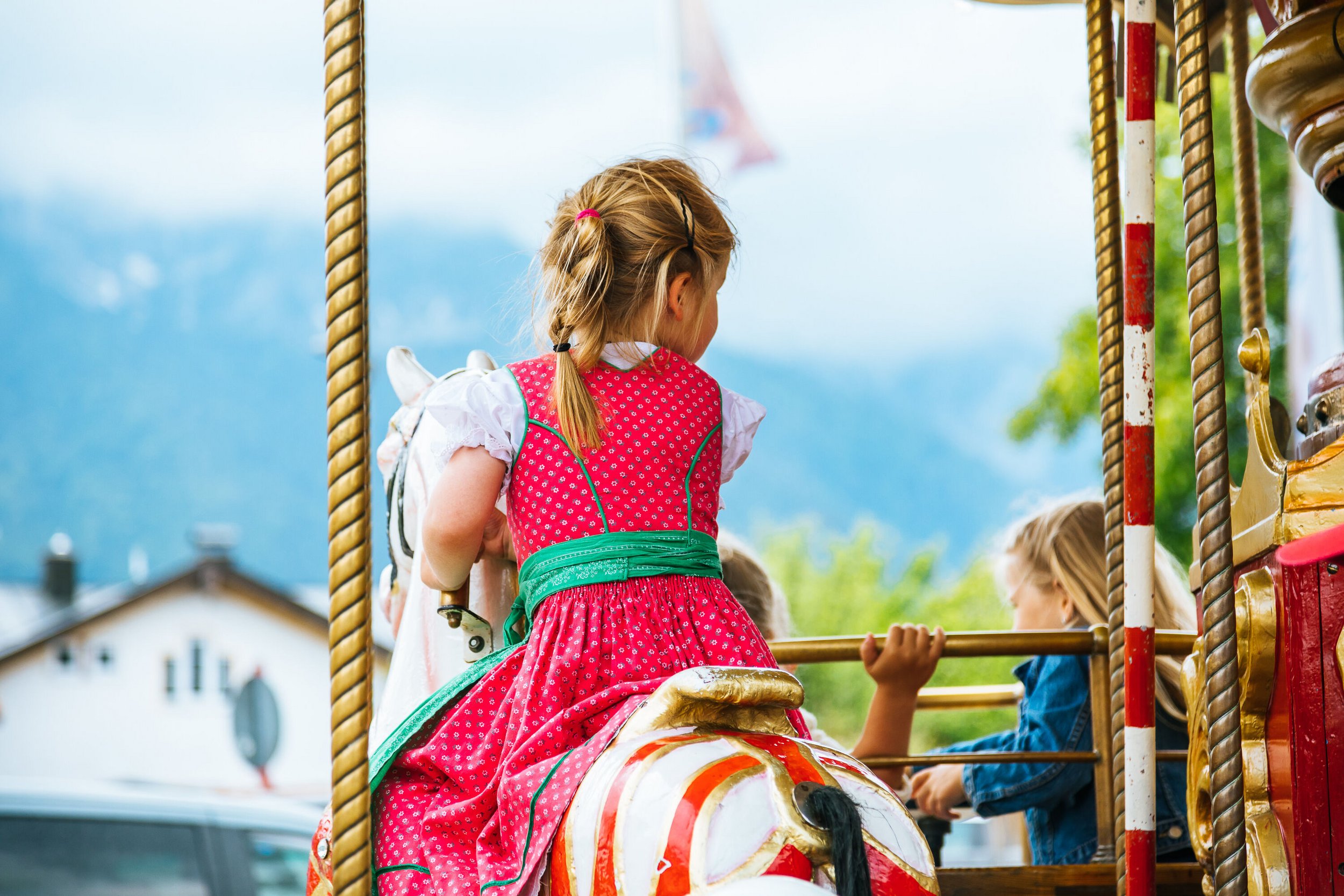 Girl in dirndl dress on a rocking horse
