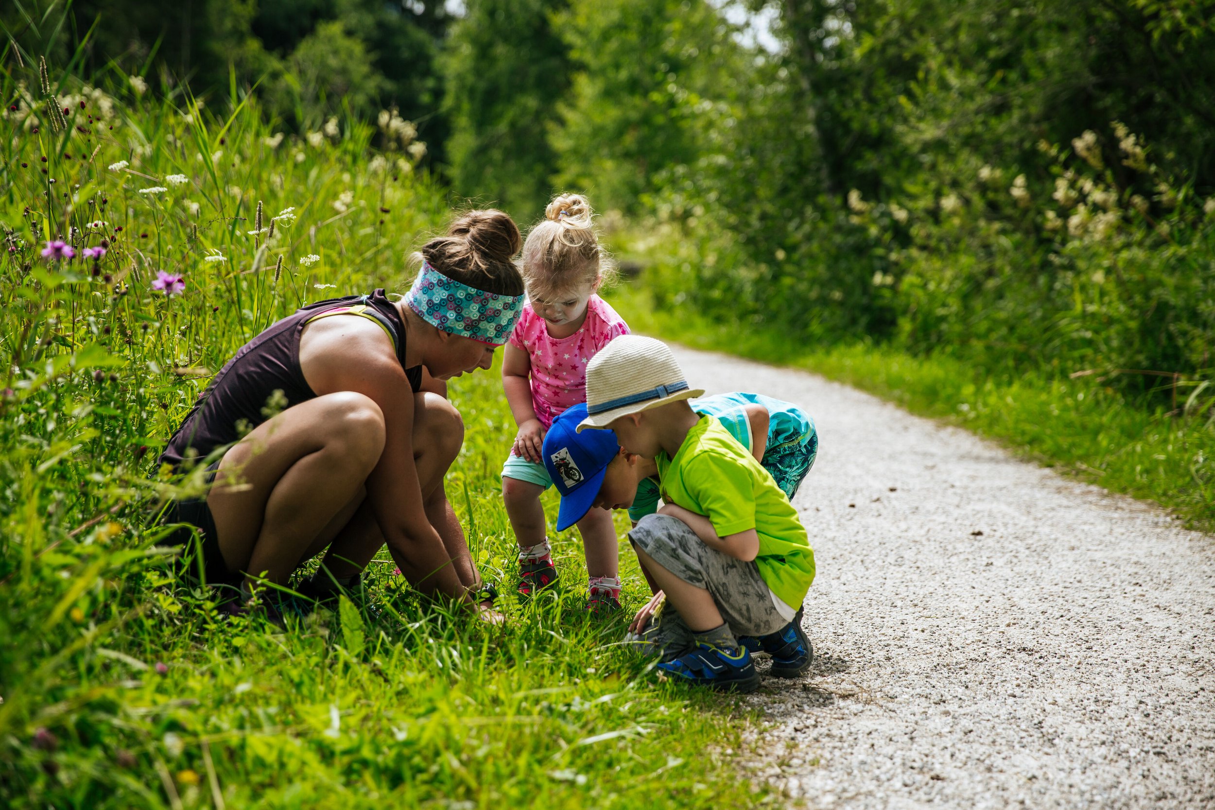 Mutter mit Kindern beim Erkunden von Wiesenpflanzen auf einem Wanderweg bei Inzell