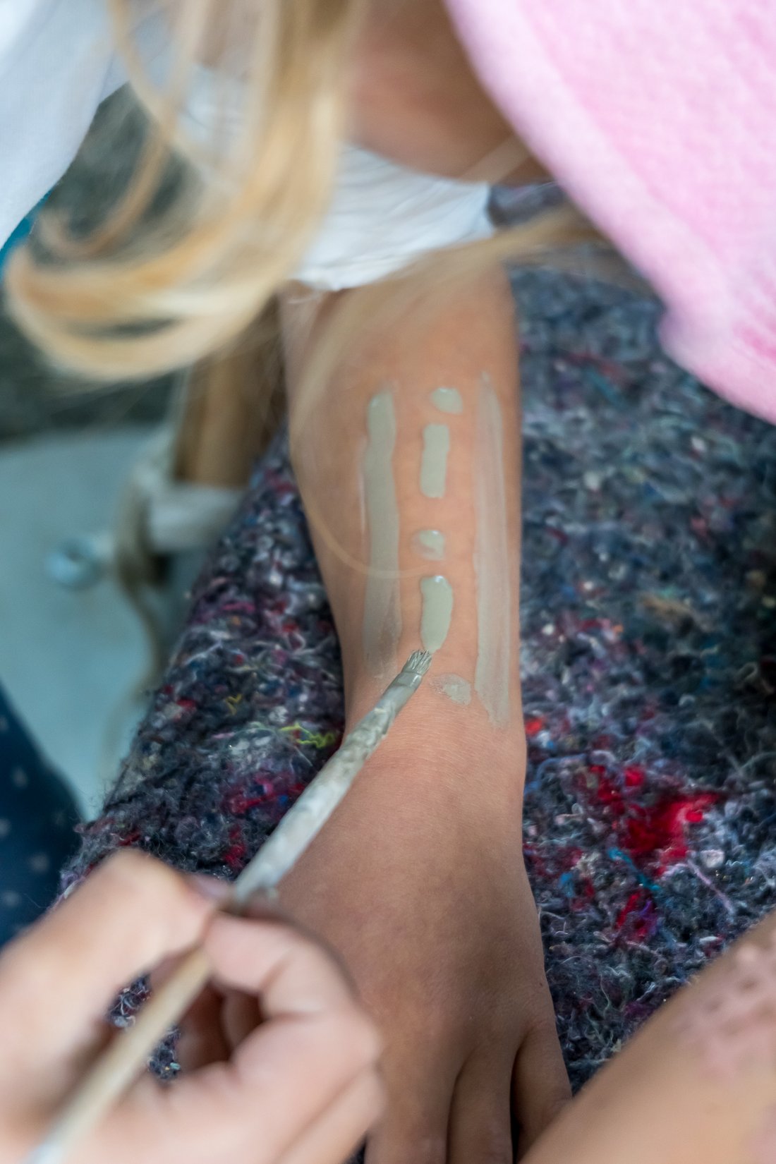 Der Arm eines Mädchen werden mit Lehmfarbe bemalt