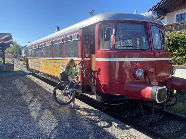 Frau lädt ein Rad in die Chiemgauer Lokalbahn ein
