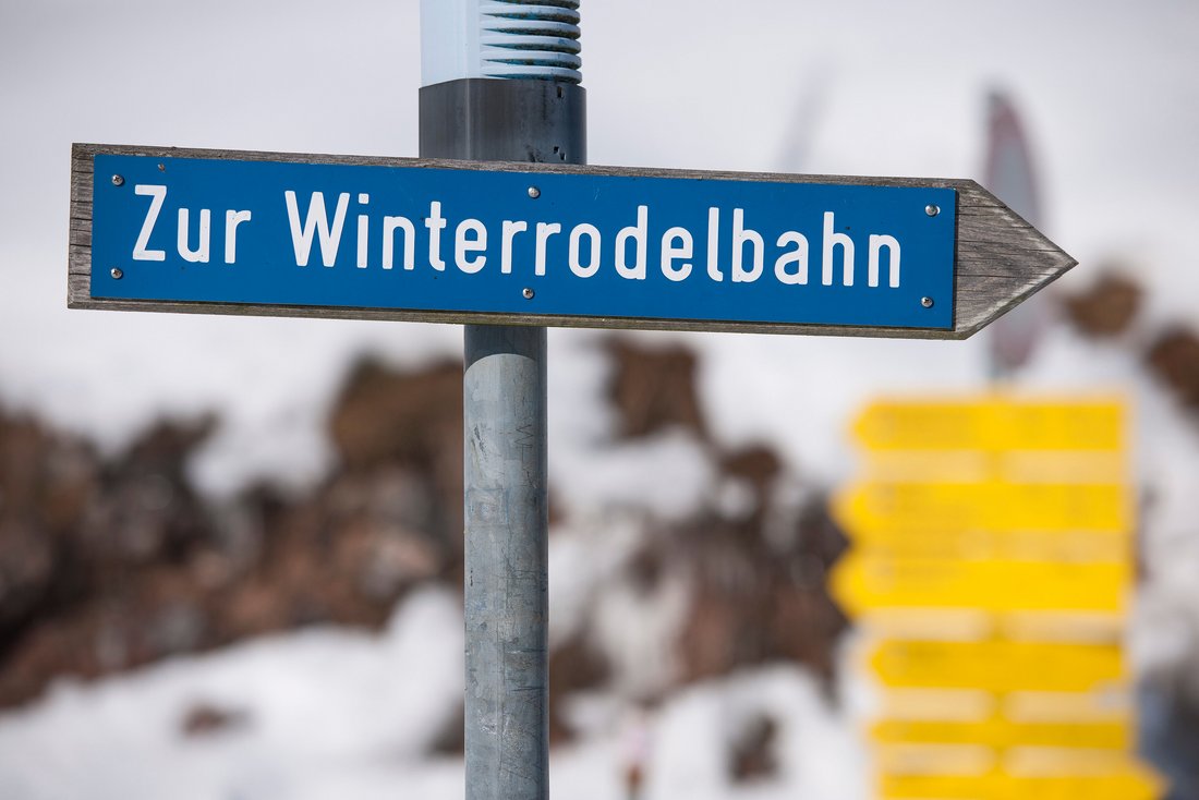 Schild mit Aufschrift "Zur Winterrodelbahn"