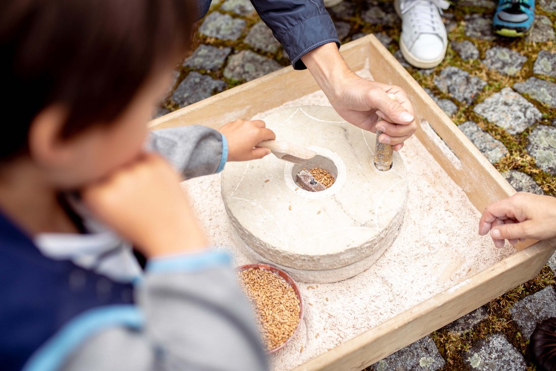 Kind mahlt Mehl mit einer Römermühle