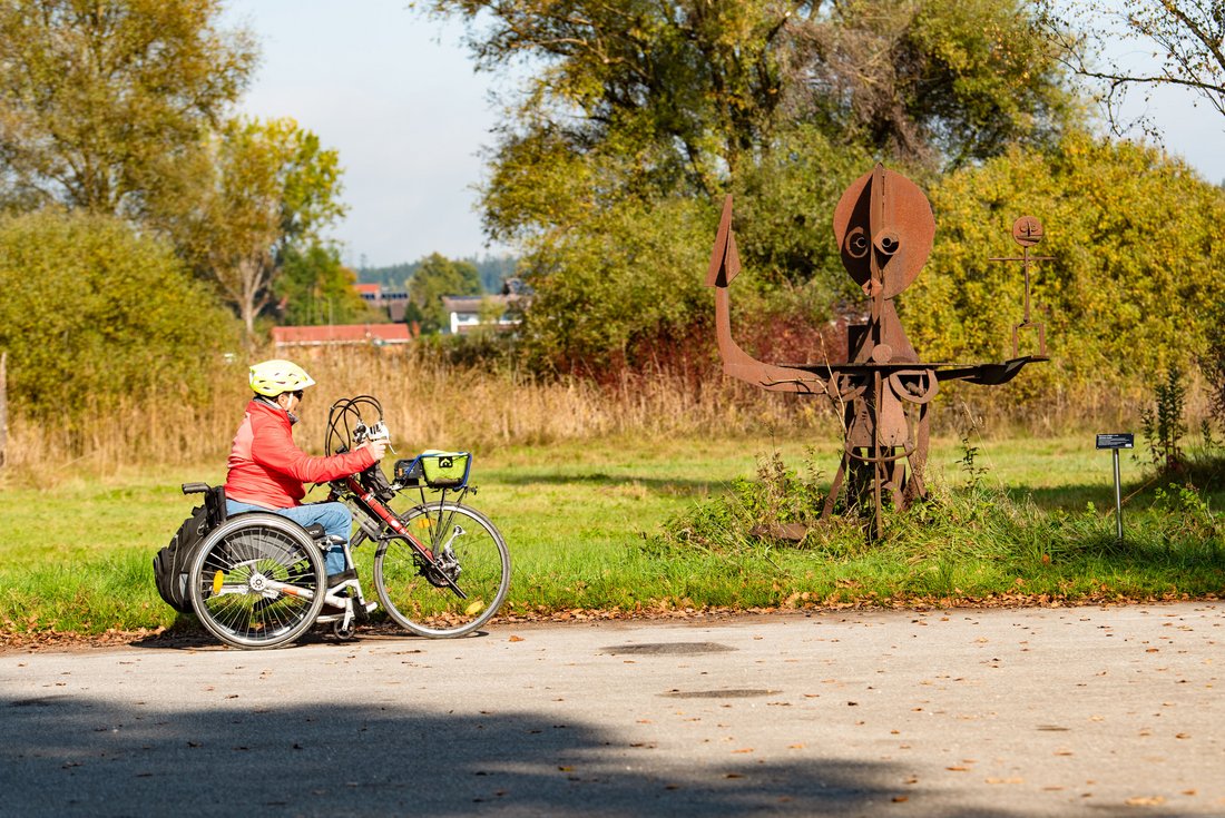Frau mit einem E-Vorspannbike auf der Handbike Tour entlang des Skulpturenwegs in Obing