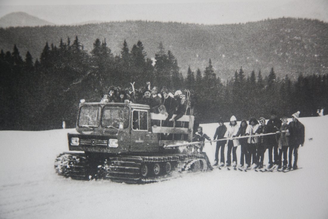 Historische Aufnahme von Skifahrern die von einer Schneeraupe gezogen werden