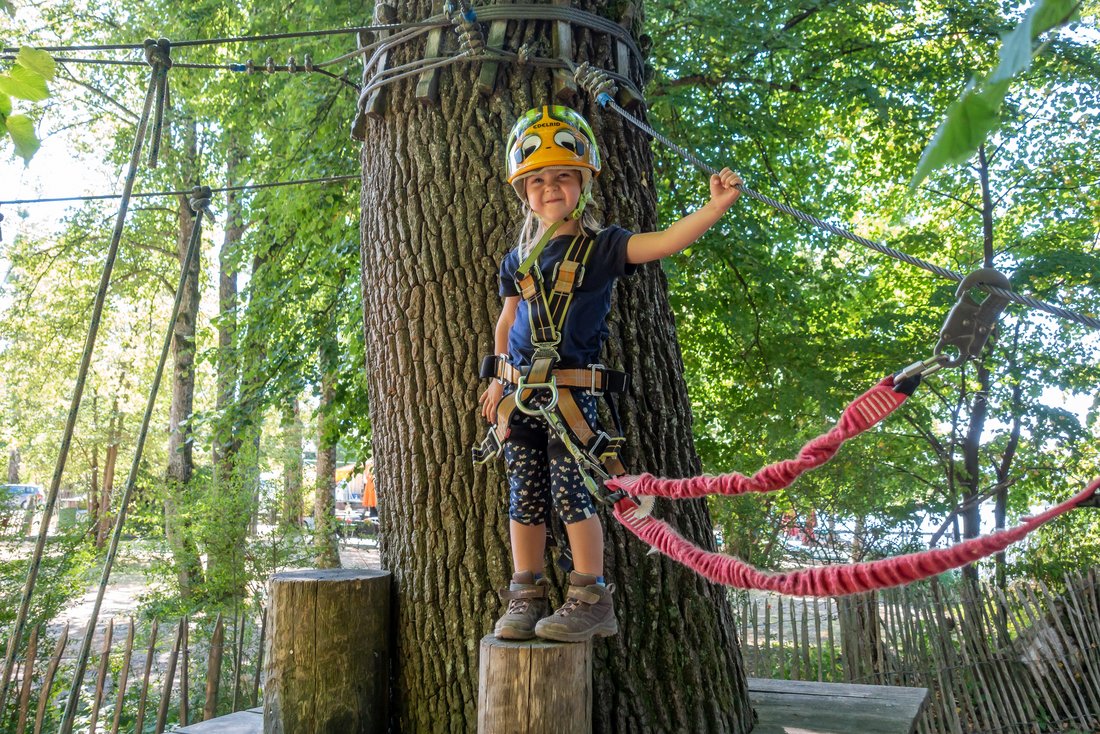 Mädchen steht auf einem Baumstumpf für dein Einstieg in den Kinderparcour im Klettergarten Übersee