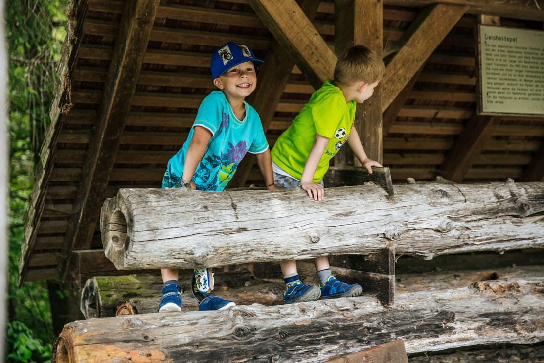 Kinder beim Toben auf Holzbalken auf einem Wanderweg bei Inzell