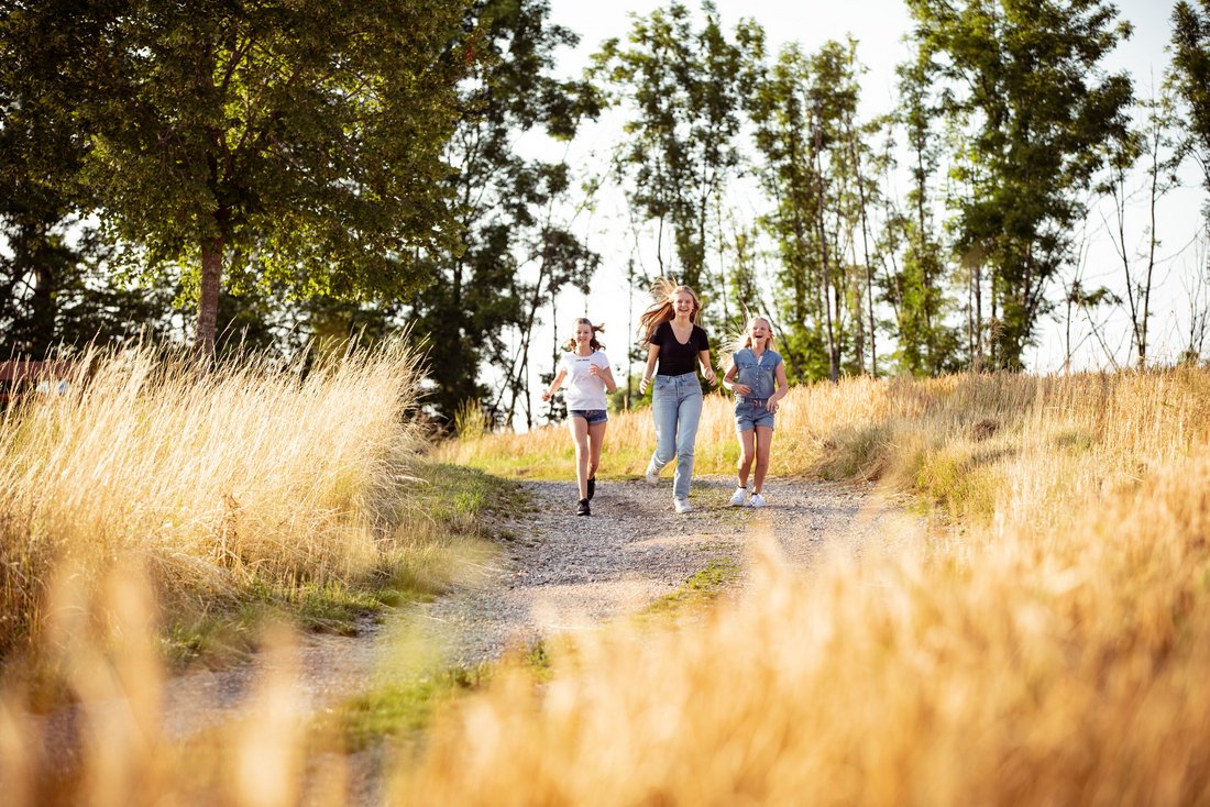 Drei junge Mädchen laufen durch ein sommerliches Feld