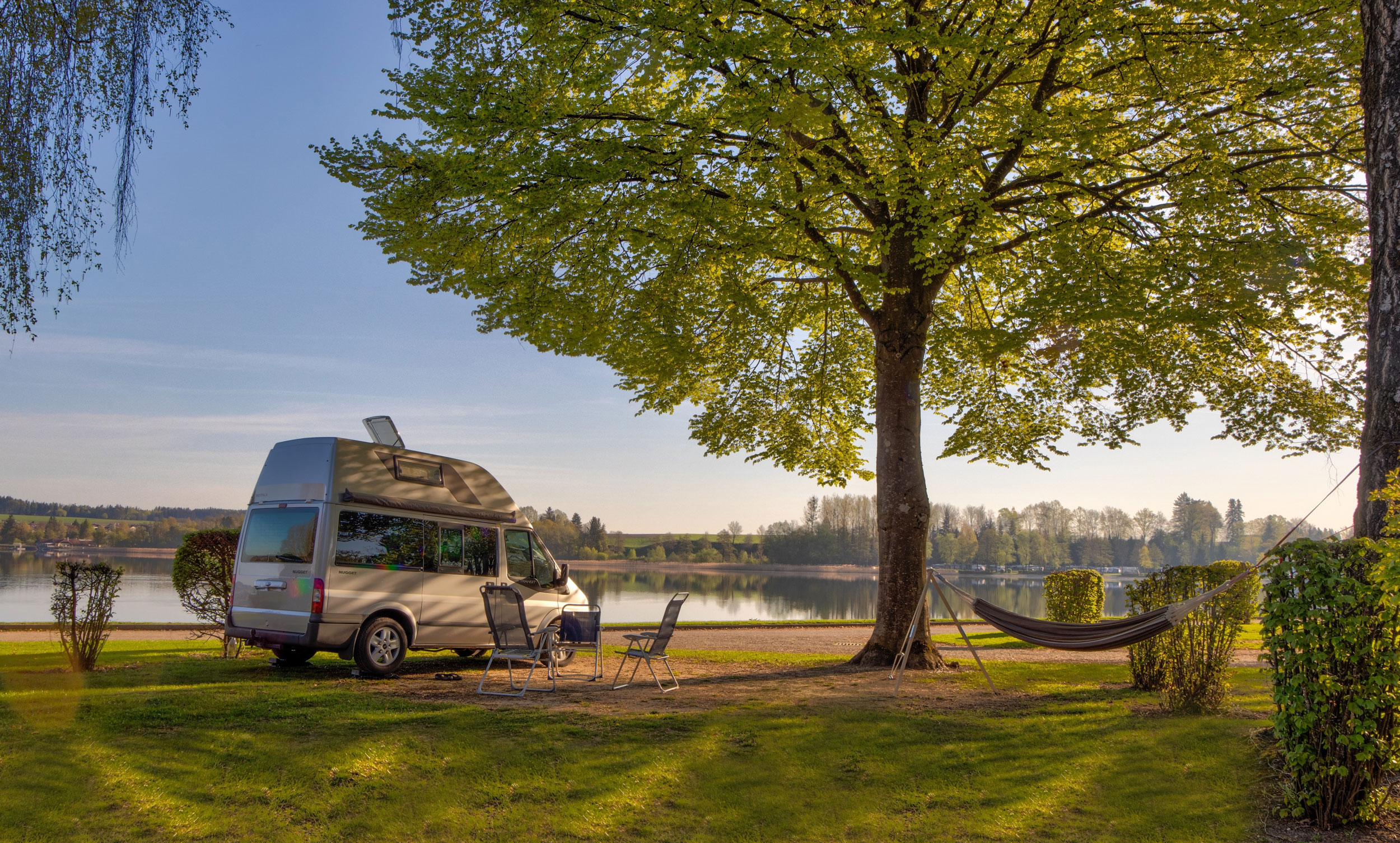 Wohnmobil auf einem Stellplatz mit Blick auf den Waginger See am Strandcamping Waging am See.