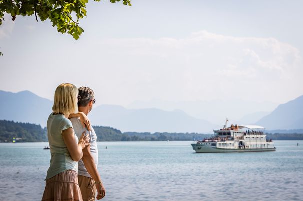 Paar schaut über den Chiemsee, im Hintergrund die Chiemsee Schifffahrt