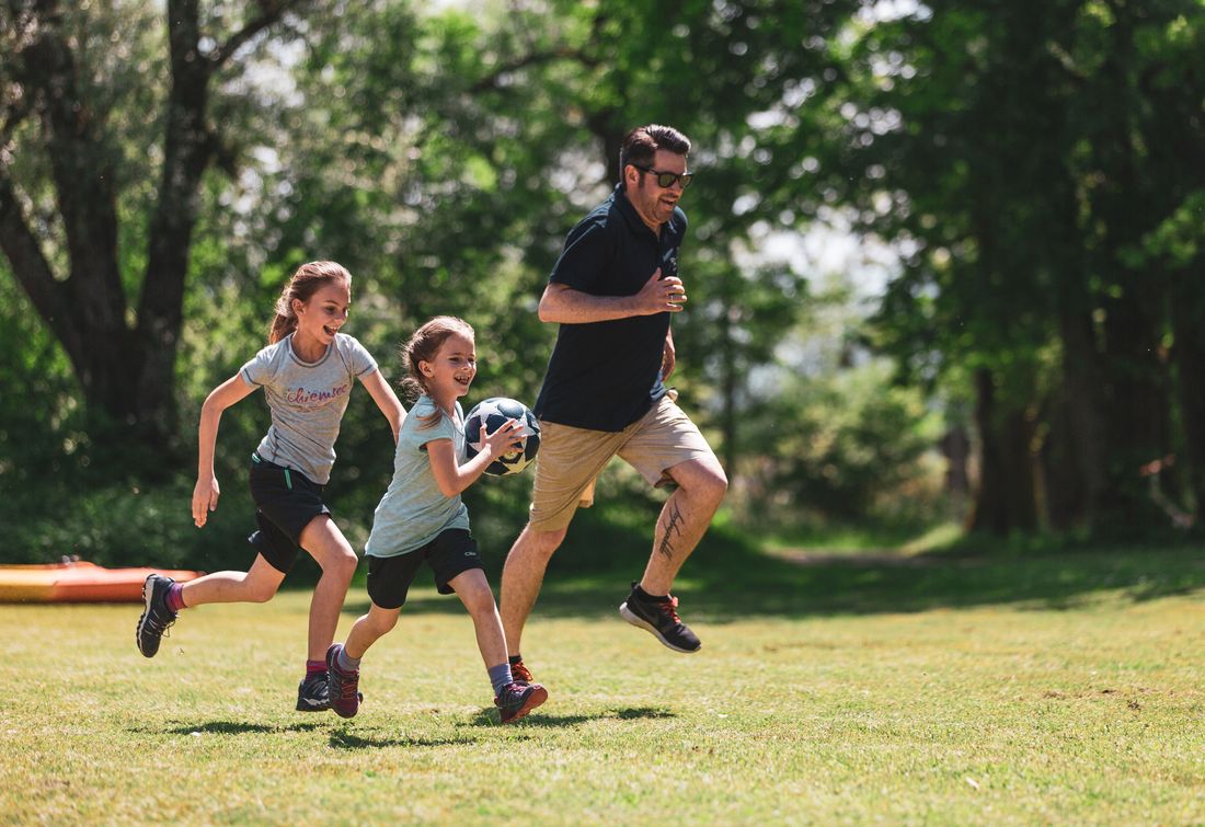 Vater spielt mit Töchtern Ball in Übersee