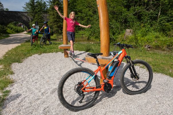 Mädchen balanciert auf einer Slackline, im Vordergrund steht ein E-MTB
