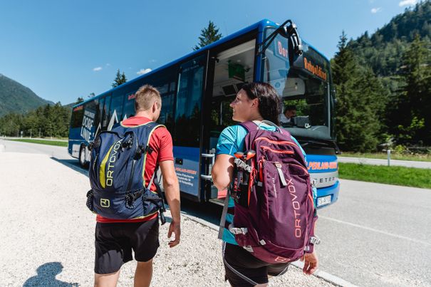 Ein Paar läuft auf den blauen Bus der Dorflinie Ruhpolding zu 