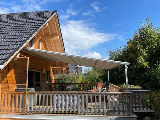 Wooden terrace on the south side with awning and access to the garden