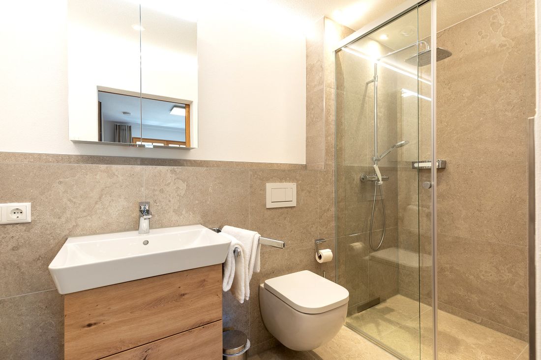 Erstes Badezimmer mit ebenerdiger Dusche und Steinboden