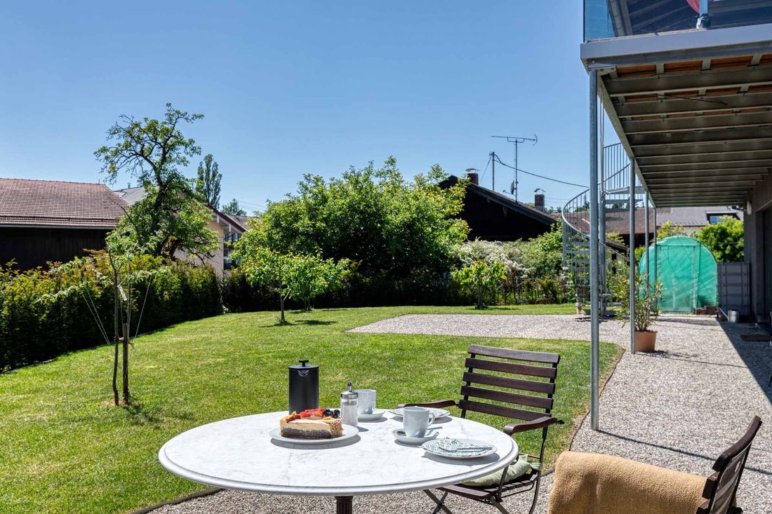 Außenansicht der Ferienwohnung Lieblingseck mit Hängematte und gedecktem Kaffeetisch in Gstadt am Chiemsee.