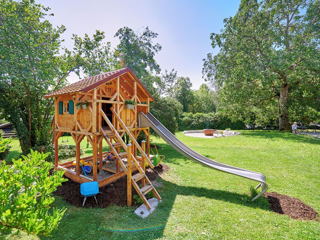 Spielhaus im Garten, im Hintergrund Grillstelle