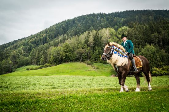 Reiter auf geschmückten Pferd auf der Wiese auf dem Weg nach Inzell