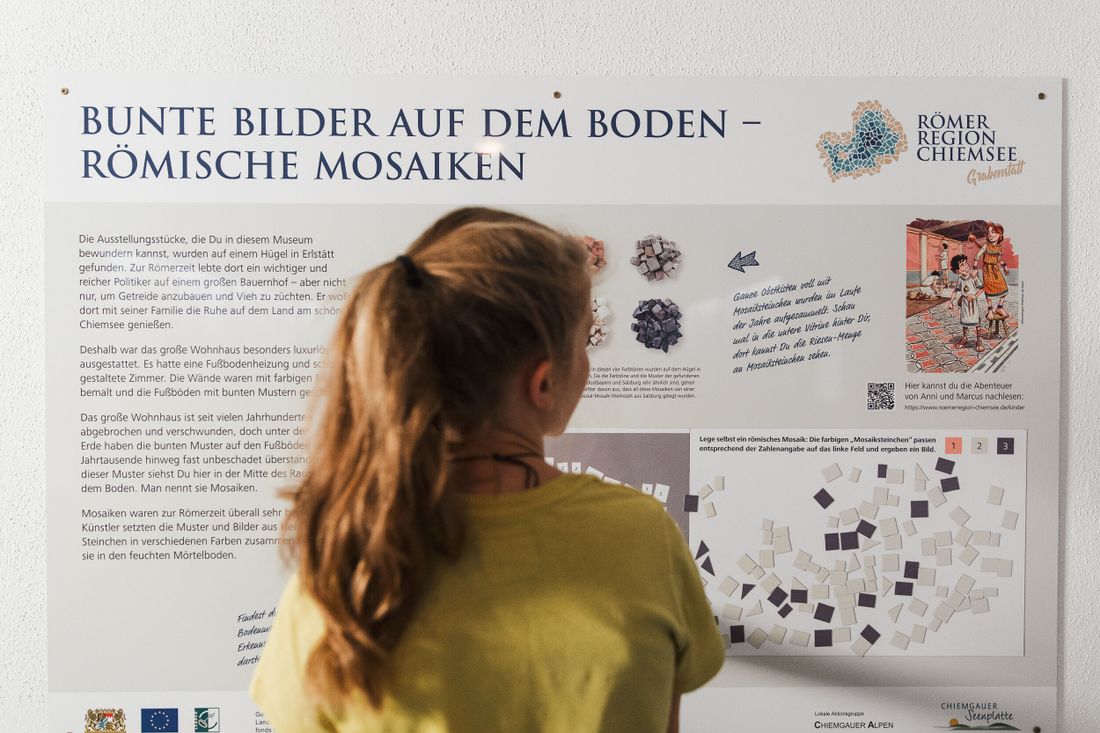 Mädchen vor einer Erklärtafel zum Thema römisches Mosaik 