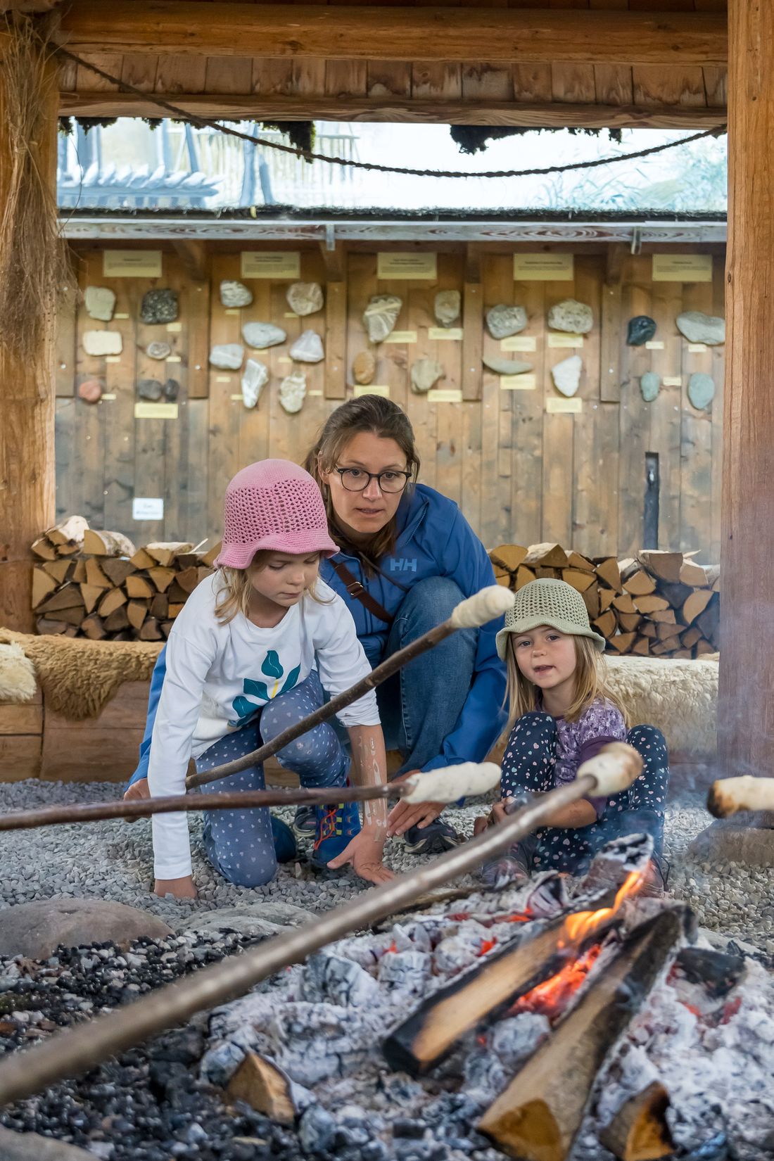 Mutter und ihre zwei Töchter backen Stockbrot im Mammutmuseum Siegsdorf