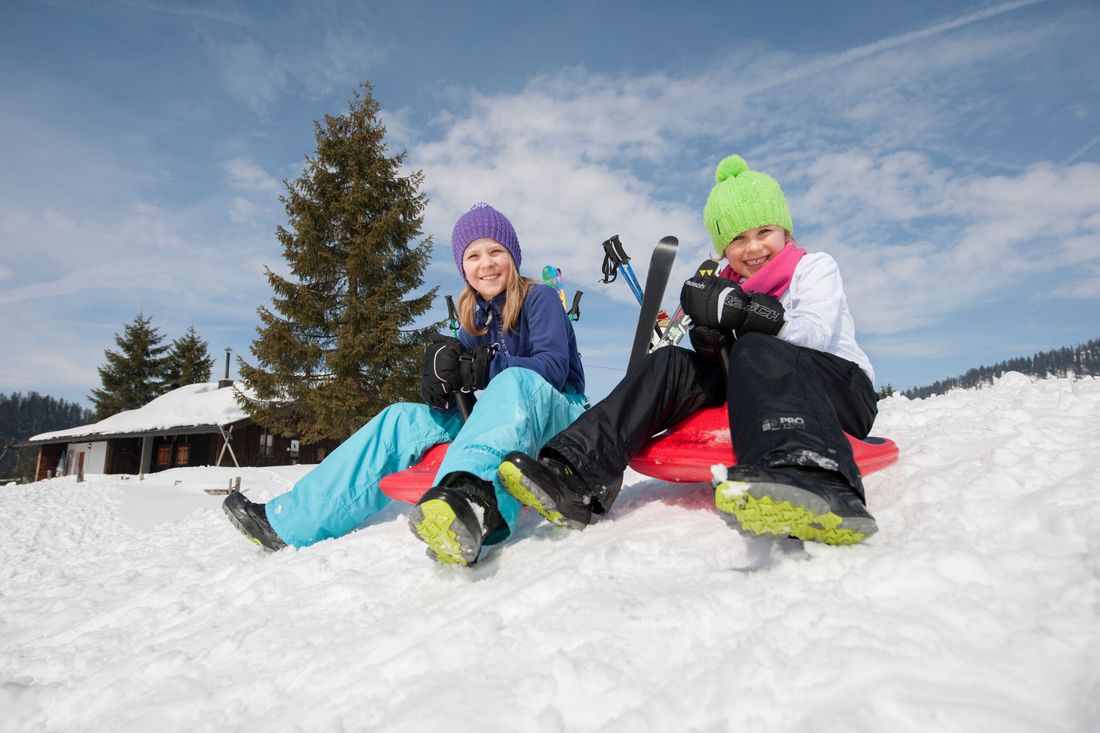 Zwei Kinder beim Rodeln im Schnee