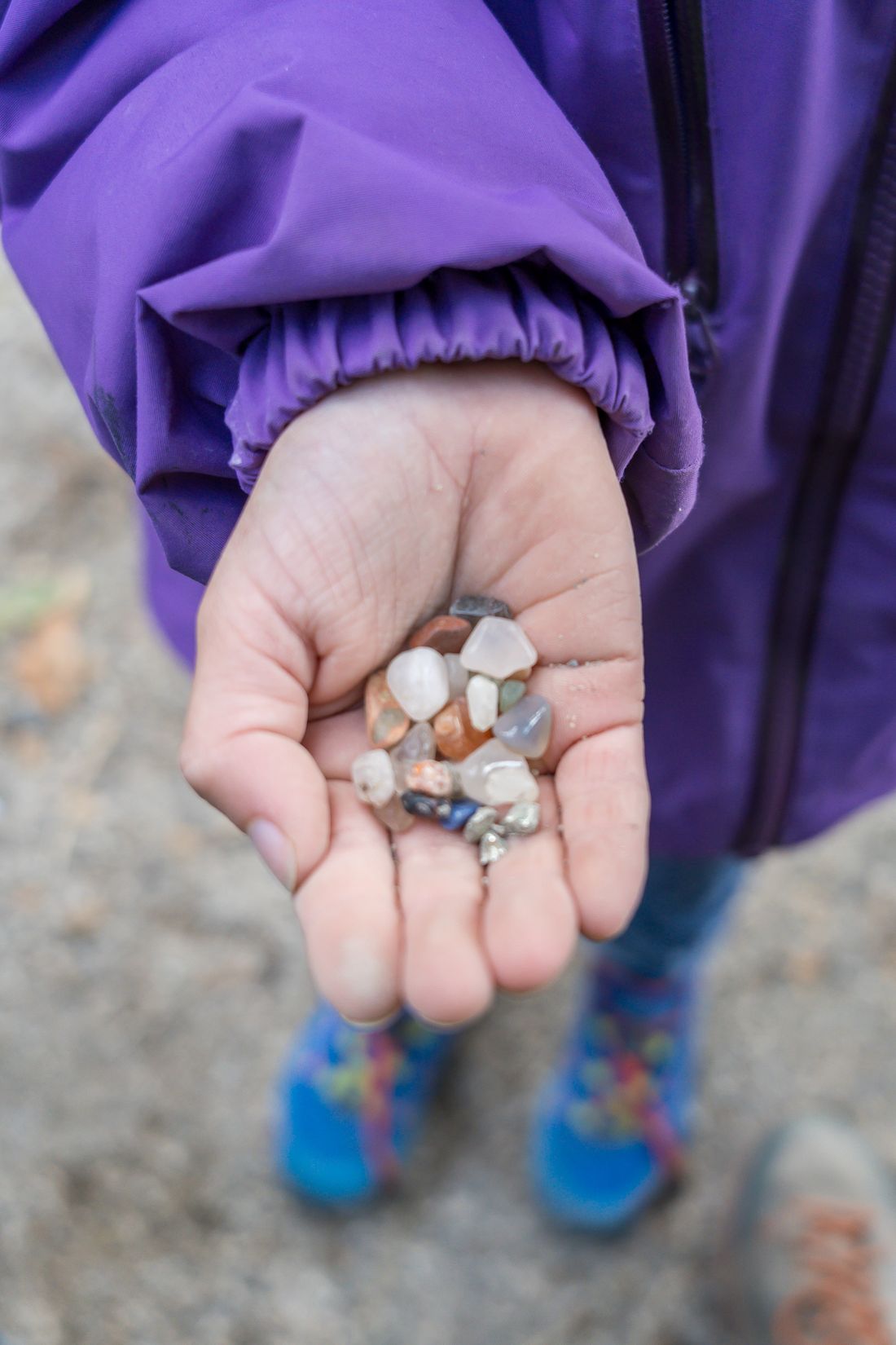 Mädchen hält viele kleine Steine in der Hand